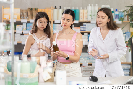 Woman with daughter choosing syrup with pharmacist Woman with daughter choosing syrup with pharmacist 125773748