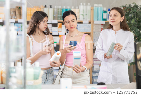 Woman with daughter scans cream qr code with pharmacist Woman with daughter scans cream qr code with pharmacist 125773752