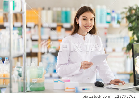 Young woman pharmacist use computer to verify information Young woman pharmacist use computer to verify information 125773762