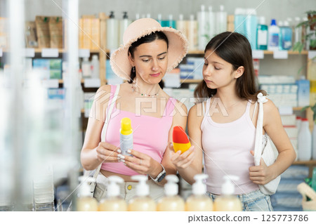 Portrait of interested mother and daughter customers preparing for summer season, holding and examines label and content of Portrait of interested mother and daughter customers preparing for summer season, holding and examines label and content of 125773786