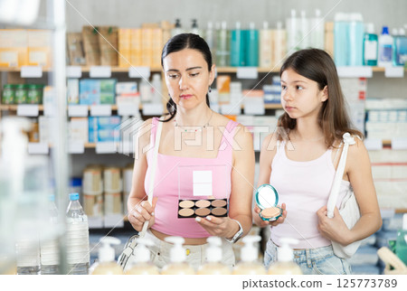 Mom and daughter choosing cosmetics in chemist's shop Mom and daughter choosing cosmetics in chemist's shop 125773789
