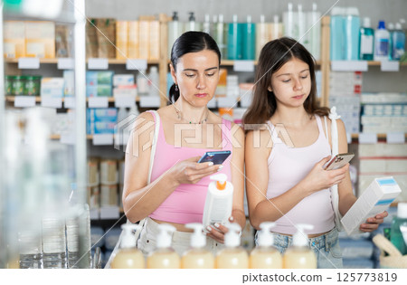 Woman and girl daughter in pharmacy scans QR code on cream Woman and girl daughter in pharmacy scans QR code on cream 125773819