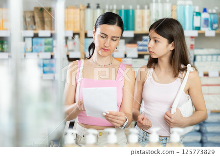 Woman with daughter in pharmacy with medical prescription 125773829
