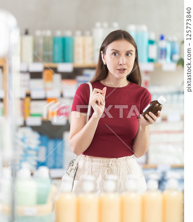 Woman choose buy expectorant syrup at pharmacy 125773840