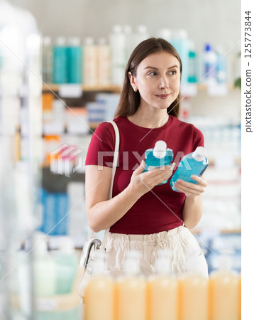 Woman choosing mouthwash at pharmacy Woman choosing mouthwash at pharmacy 125773844