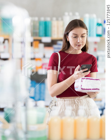 Woman scans package of pads in pharmacy Woman scans package of pads in pharmacy 125773845