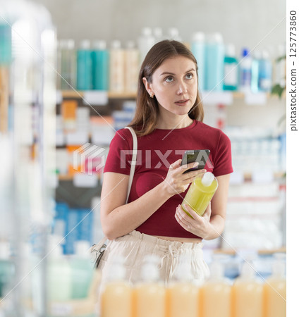 Young woman scanning qr code of shampoo or shower gel Young woman scanning qr code of shampoo or shower gel 125773860