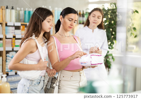 Woman with daughter choosing feminine pads with pharmacist 125773917