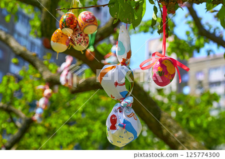 Bright bunch of colorful painted Easter eggs on green spring tree 125774300
