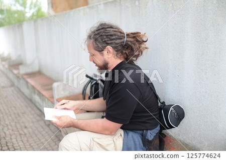Sound technician writing notes outdoors during a break 125774624
