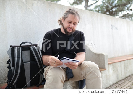 Writer taking notes outdoors in urban setting 125774641
