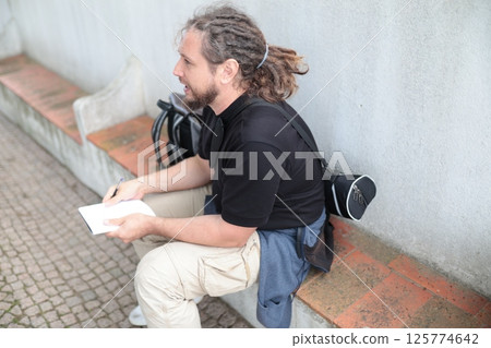 Journalist writing notes while interviewing someone outdoors Journalist writing notes while interviewing someone outdoors 125774642