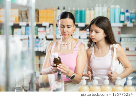 Mom and daughter customer choosing syrup in drugstore 125775284