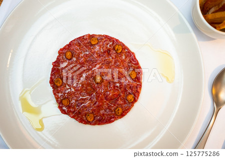Exquisite French dish is veal tartare decorated with pickled capers 125775286