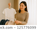 A young Japanese woman drying clothes indoors 125776099