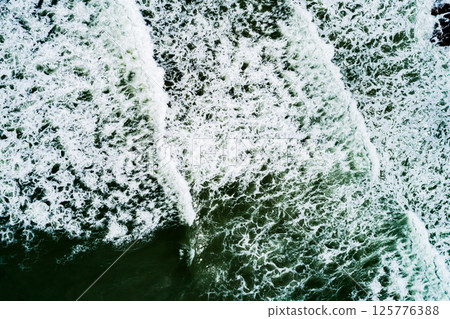 Top view Dark waves crashing on sandy shore beach background,Amazing waves sea nature background Top view Dark waves crashing on sandy shore beach background,Amazing waves sea nature background 125776388