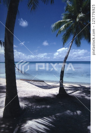 Hammock on the sandy beach with a view of the blue sea 125776925