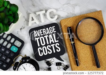 ATC - Average Total Costs acronym with calculator, alarm clock and magnifying glass, Business concept background 125777372