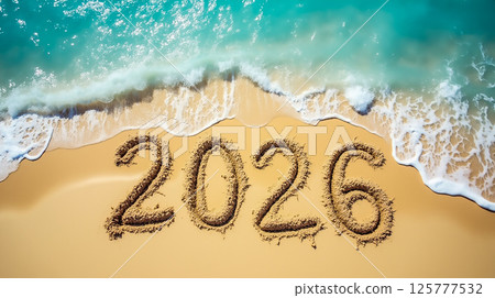 Sand writing of the year 2026 on a sunny beach with gentle waves lapping at the shore 125777532