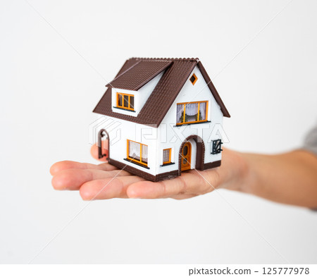 Woman is holding a mini toy house in her hand. Real estate concept. Woman is holding a mini toy house in her hand. Real estate concept. 125777978