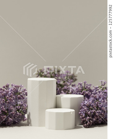 Elegant minimalistic spring-themed product display with white geometric pedestals surrounded by fresh lilac flowers Elegant minimalistic spring-themed product display with white geometric pedestals surrounded by fresh lilac flowers 125777992