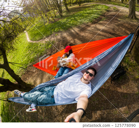 young family Relaxing in Hammocks on a Sunny Day young family Relaxing in Hammocks on a Sunny Day 125778090