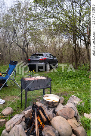 Camping Scene with Car, Grill, and Campfire in Forest Camping Scene with Car, Grill, and Campfire in Forest 125778099