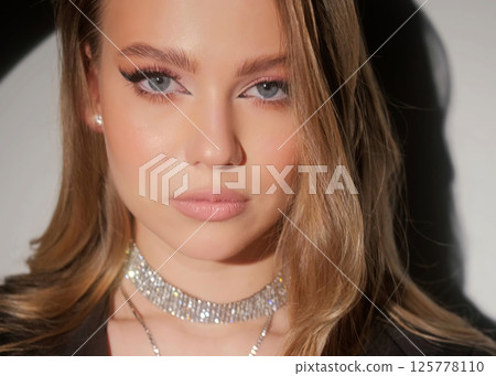 Beautiful blonde in a black jacket and luxurious jewelry around her neck. Beauty portrait and accessories. 125778110