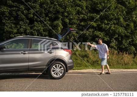 Man with Backpack at Open Car Trunk 125778111