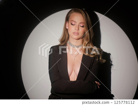 Beautiful blonde in a black jacket and luxurious jewelry around her neck. Beauty portrait and accessories. 125778112
