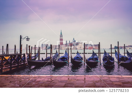 Gondolas in Venice with Abbey of San Giorgio Maggiore in the background. Ferry Gondola Pier. Venice, Italy Gondolas in Venice with Abbey of San Giorgio Maggiore in the background. Ferry Gondola Pier. Venice, Italy 125778233