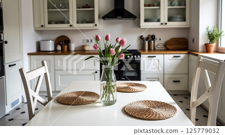Modern kitchen with pink tulips on white table showcasing a cozy atmosphere and minimalist design during daylight 125779032