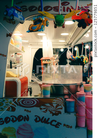 Nighttime cotton candy concession stand with candy display and colorful toys. Spain Square, Plaza de 125779851