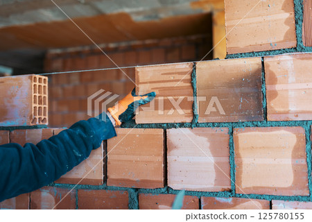 Bricklayer worker installing bricks on construction site Bricklayer worker installing bricks on construction site 125780155