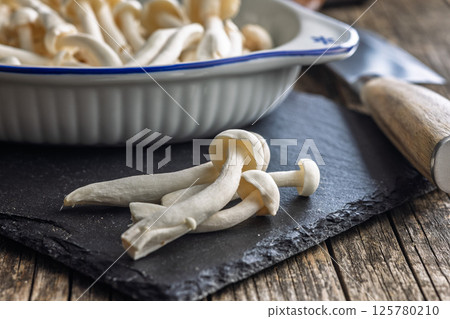 Raw white shimeji mushrooms on cutting board. Raw white shimeji mushrooms on cutting board. 125780210