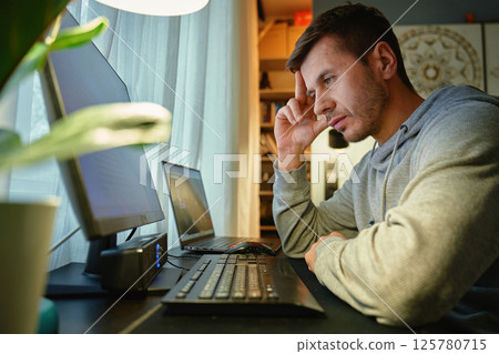 Man procrastinating at workplace while browsing on computer Man procrastinating at workplace while browsing on computer 125780715