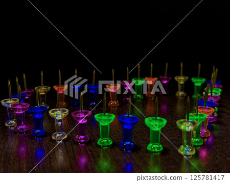 Neon Push Pins in a Heart Formation on Dark Wood 125781417
