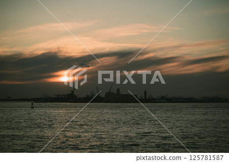 A stunning sunset lights up the water with a city skyline behind A stunning sunset lights up the water with a city skyline behind 125781587