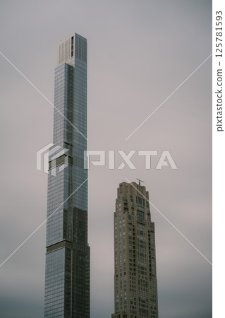 Two tall buildings stand next to each other on a cloudy day Two tall buildings stand next to each other on a cloudy day 125781593