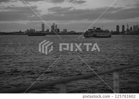 A black and white photo of a ferry with a city skyline 125781602