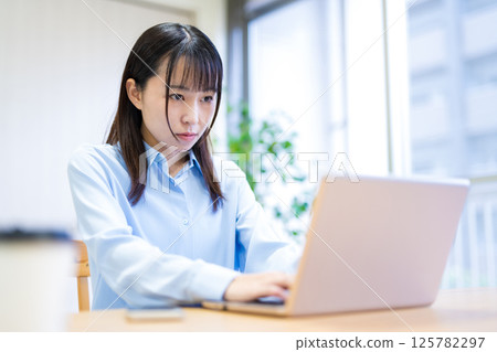 一位年輕女子在客廳遠距工作，嚴肅認真 125782297