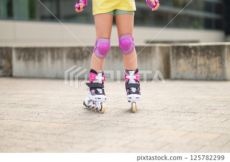 Unrecognizable child skating on roller-blades in stadium having fun 125782299