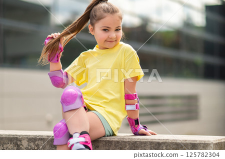 Child in roller-skates sitting in stadium resting Child in roller-skates sitting in stadium resting 125782304