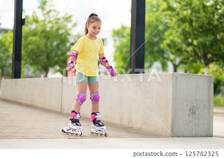 Child skating on roller-skates in the stadium showing off her skills Child skating on roller-skates in the stadium showing off her skills 125782325