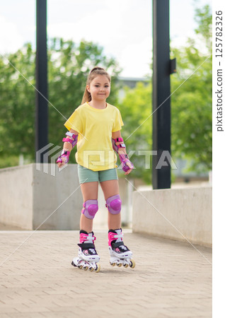 Girl roller-blading outside mastering skating moves while having fun Girl roller-blading outside mastering skating moves while having fun 125782326