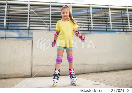 Little girl roller-skating outside in stadium Little girl roller-skating outside in stadium 125782330