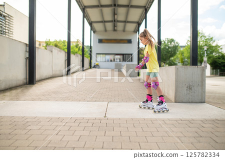 Little female skater riding roller-blades outdoors having fun Little female skater riding roller-blades outdoors having fun 125782334