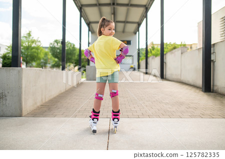 Little girl roller-skating outside in stadium 125782335