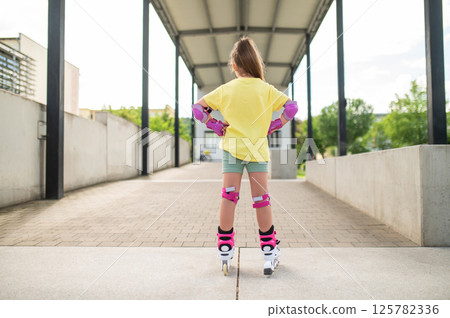 Little female skater riding roller-blades outdoors having fun 125782336