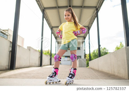 Little female skater riding roller-blades outdoors having fun Little female skater riding roller-blades outdoors having fun 125782337